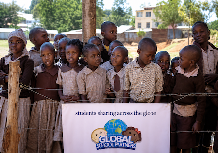 Pupils with Global School Partners banner — students sharing across the globe